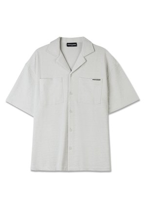 Camicia grigia chiara a maniche corte con tessuto testurizzato, due tasche anteriori e colletto a punta. Presenta il logo "PEGADOR" sul petto.