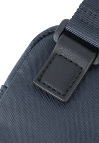 Detail van een marineblauwe stoffen tas met een textuur, voorzien van een zwart leren accent en een stevige strapverbinding.