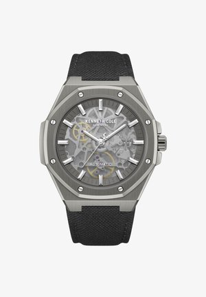 Samodejna zapestna ura Kenneth Cole s črnim tkanim paščkom, prozornim številčnico, ki prikazuje notranja gonila, srebrnim šestkotnim okvirjem in svetlečimi kazalci.