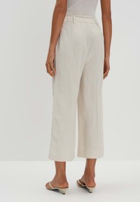 Lichtbeige brede broek met een elastische tailleband, met een gladde structuur en een rechte snit die net boven de enkel valt.