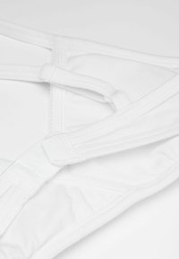 White fabric bra with adjustable straps, featuring a soft texture and elastic bands. Includes hook-and-eye closure and decorative stitching details.