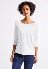 Witte, langemou shirt van katoen met een ronde hals. Het heeft een gladde textuur, een casual pasvorm en is gecombineerd met donkere spijkerbroek.