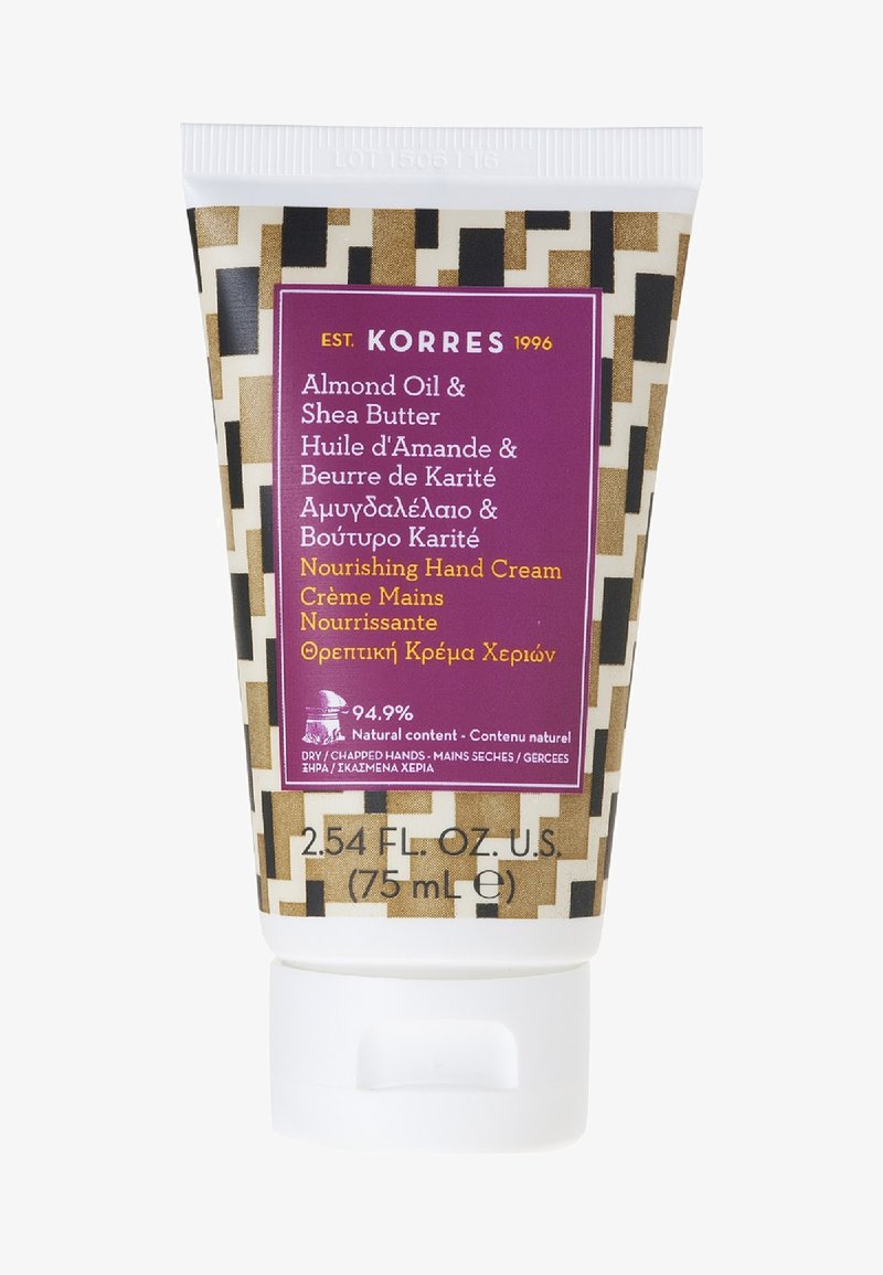 Witte plastic tube met een hoekig patroon in bruin en crème, paarse label met de tekst "Voedende Handcrème" met amandelolie en sheaboter als ingrediënten.