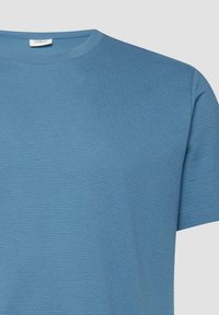 T-shirt en maille bleu à manches courtes avec encolure ronde et texture horizontale subtile, montrant le haut devant et la manche droite.