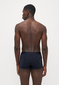 Férfi sötétkék boxer alsónadrág zöld Lacoste logó mintával, egyszínű derékrésszel és sima pamut anyaggal. Látható varrási részletek.