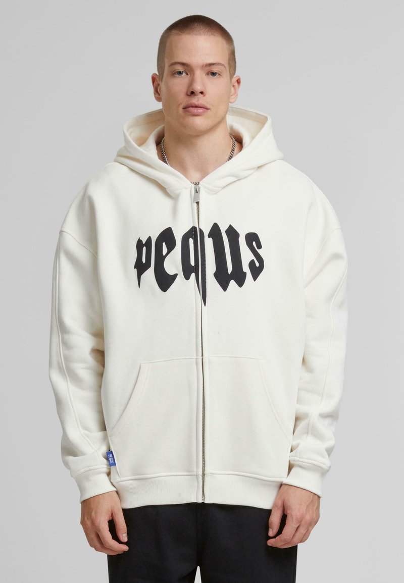 Witte zip-up hoodie met een grote zwarte grafische print op de borst. Voorzien van een trekkoordkap en zijzakken. Zachte stoftextuur.