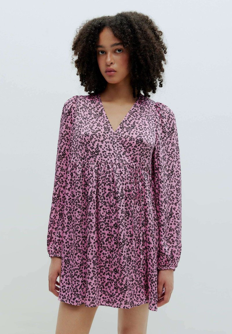 Rosa langärmliges Kleid mit V-Ausschnitt, präsentiert ein schwarzes Leopardenmuster, geraffte Taille und strukturierter Stoff.