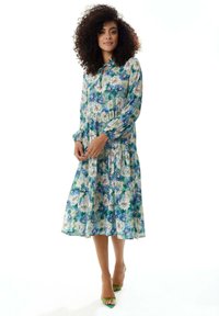 Floral midi dress in blue and green, with long sleeves and a keyhole neckline. Made from lightweight fabric with a pleated design.