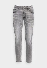 Grå denimjeans med smal passform, med slitna områden, blekt textur och spridda färgglada fläckar. Standarddesign med fem fickor.