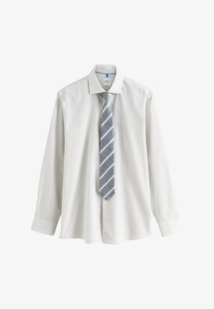 Balta ilgomis rankovėmis palaidinė su šviesiai mėlynomis juostelėmis ir sagomis ant rankogalių, derinama su mėlyną kaklaraištį, puoštu įstrižomis baltomis juostelėmis.