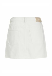 Bela denim krilna z fitted pasom, dvema zadnjima žepoma in svetlo rjavim etiketom na pasu. Ima ravno obrobo in preprosto šivanje.