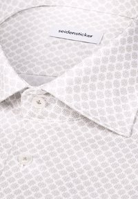 Chemise blanche à petit motif géométrique, col boutonné, avec une étiquette "seidensticker" à l'intérieur du col.
