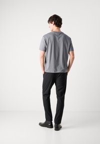 Grå bomulls t-shirt, kortärmad, avslappnad passform, kombinerad med svarta slim-fit byxor och svarta läderankelstövlar. Minimalistisk stil.