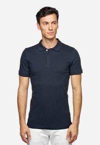 Camisa polo azul marino, de mangas cortas, con tapeta de botones, fabricada en suave algodón, de corte ajustado, diseño liso, con una textura sutil.