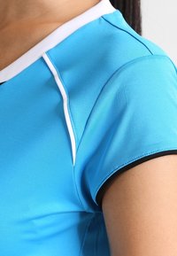 Blaues Sportshirt mit kurzen Ärmeln, ausgestattet mit einem weißen Kragen und schwarzem Saum. Glatte Textur, taillierte Passform und keine sichtbaren Muster.