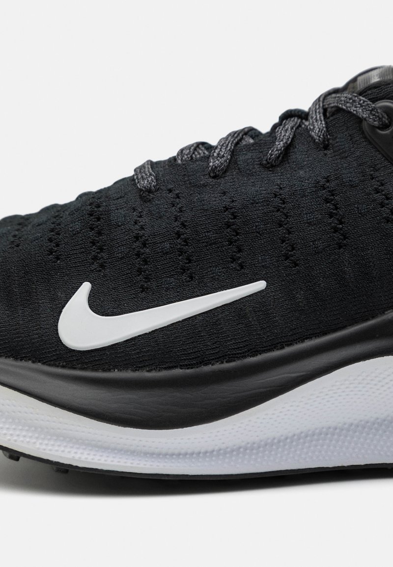 Czarny but sportowy z teksturowanej tkaniny, z białym logo swoosh i szarymi sznurówkami. Niskoprofilowy design z czarną podeszwą.