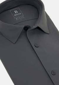 Camisa de dress gris hecha de una tela suave, con un cuello puntiagudo, botones negros y una etiqueta sutil que indica la marca y la talla.