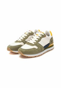 Zapatillas verdes y blancas con materiales de ante y malla, con un acento azul marino y una lengüeta amarilla en el talón. Suela de goma con agarre texturizado.