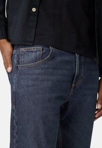 Donkerblauwe spijkerbroek met een comfortabele pasvorm, voorzien van contrasterende stiksels, vijf zakken en een gladde textuur. Accentueert subtiele details op de naden.