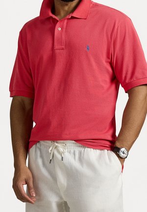 Czerwona koszulka polo z teksturowanej tkaniny, charakteryzująca się klasycznym krojem, z trzema guzikami i małym niebieskim logo na piersi.