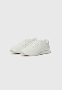 Sneakers bianchi con un motivo testurizzato, punta rotonda e chiusura con lacci. Presentano una suola in gomma bianca e materiali lisci.