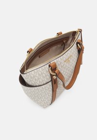 Strukturierte Handtasche aus cremefarbenem Canvas mit Monogramm-Muster, braunen Lederakzenten, goldenen Beschlägen und einem Reißverschluss. Das Innere umfasst eine Reißverschlusstasche.