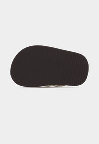 Σολάρι σαμπό με μαύρο, ραβδωτό ελαστικό πέλμα σε λευκό φόντο, αναδεικνύοντας την κάτω όψη του παπουτσιού.