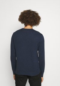 Marineblauer, langärmeliger Pullover mit rundem Halsausschnitt, gerippten Bündchen und Saum, glatter Textur und einem leicht längeren Rückenschnitt.