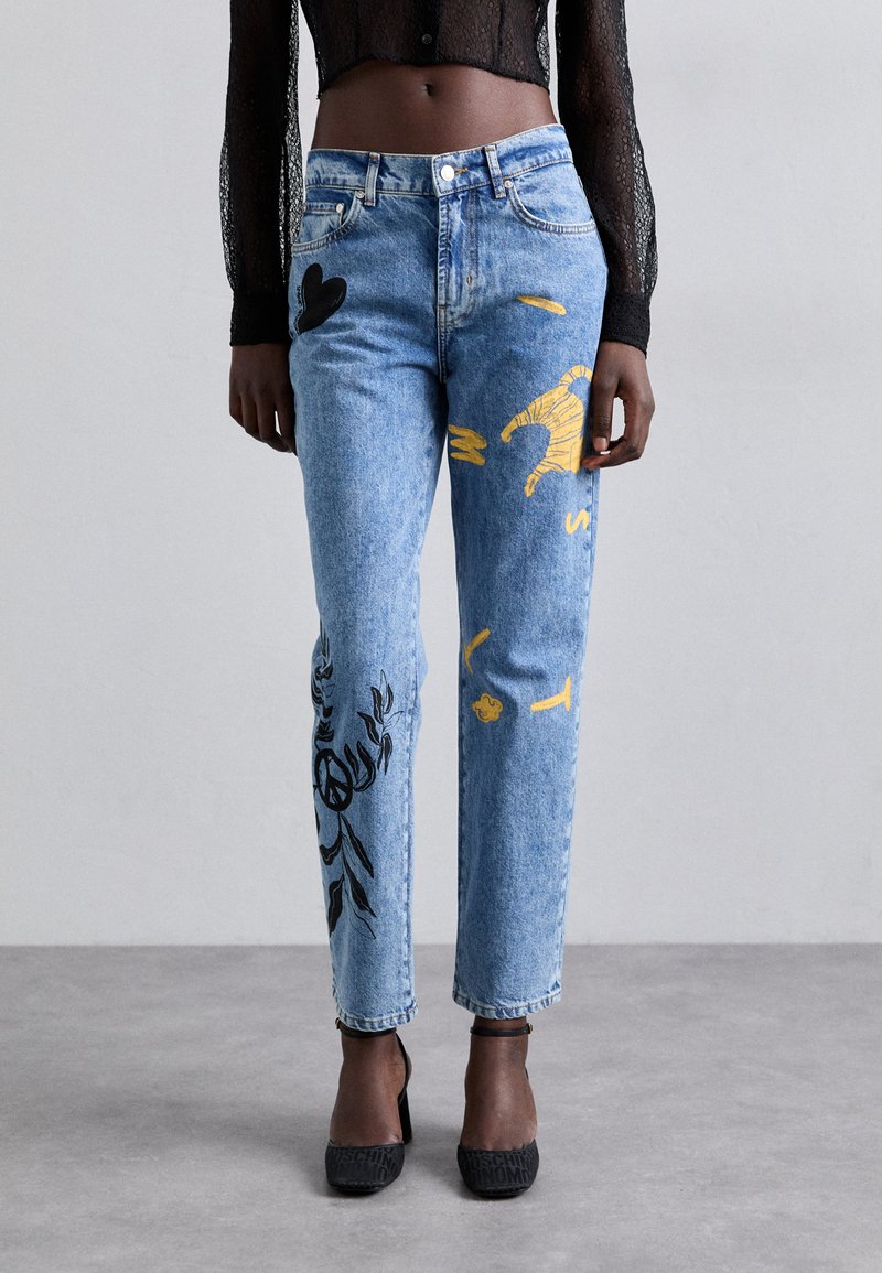 Šviesiai mėlynos džinsinės kelnės su grafika geltonos ir juodos spalvų. Aukštu liemeniu, tiesios kojos dizainas su įvairiomis dekoracijomis ant kiekvienos kojos.