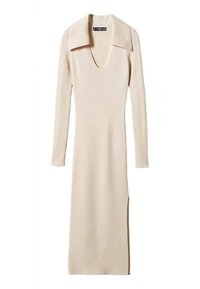 Knie-lange, geribbelde, crèmekleurige jurk met een diepe V-hals en brede kraag. Lange mouwen en zijsplitten voor meer bewegingsvrijheid.