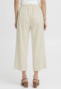 Lichtbeige, wijde broek met een elastische tailleband, gemaakt van een gestructureerde stof. De zoom is boven de enkel geknipt voor een ontspannen pasvorm.