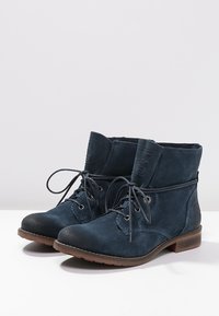 Ciemnoniebieskie zamszowe botki za kostkę z okrągłym noskiem, sznurowanym przodem, przeszyciami i teksturowaną brązową gumową podeszwą. Regulowana wysokość kostki.
