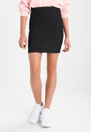 Musta polka dot -kuvioitu hame, istuva malli, polven pituinen. Yhdistetty valkoisiin tennareihin. Yksinkertainen ja monikäyttöinen kuvio korostaa kokonaisilmettä.