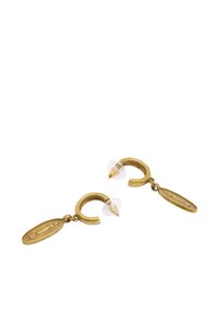 Złote kolczyki w kształcie okrągłej obręczy, z wiszącym owalnym charms'em grawerowanym w wzór i przezroczystymi plastikowymi zapięciami.