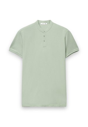 Jasnozielona koszulka polo z krótkim rękawem, z kołnierzem typu mandarynka, plisą na trzy guziki i obszytymi rękawami. Miękka bawełniana tkanina o gładkiej fakturze.