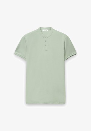 Jasnozielona koszulka polo z krótkim rękawem, z kołnierzem typu mandarynka, plisą na trzy guziki i obszytymi rękawami. Miękka bawełniana tkanina o gładkiej fakturze.