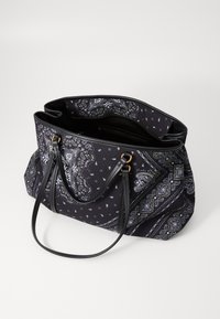 Zwarte schoudertas met paisley- en geometrische patronen, uitgerust met dubbele leren handvatten en een open bovenkant die een ritssluiting binnenzak toont.
