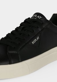 Baskets en cuir noir avec lacets noirs et semelle écrue, avec le texte "REPLAY" sur le côté et sur la languette.