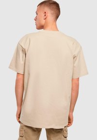 Beige bavlněné tričko s uvolněným střihem a krátkým rukávem. Kulatý výstřih a hladký povrch. Žádné viditelné logo nebo vzory.