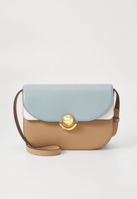 Värikäs olkalaukku, jossa on vaaleansininen läppä, valkoinen koriste ja tan-nahkainen runko. Edessä on kultaiset pyöreät metalliosat ja ohut olkahihna.