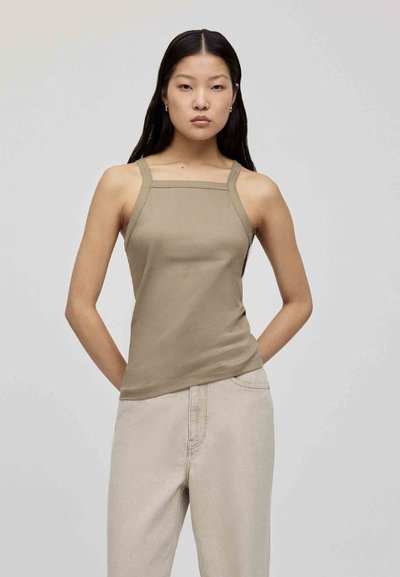Top a canotta beige a coste con scollo quadrato e spalline sottili, abbinato a pantaloni chiari con vestibilità rilassata. Texture morbida, design minimale.