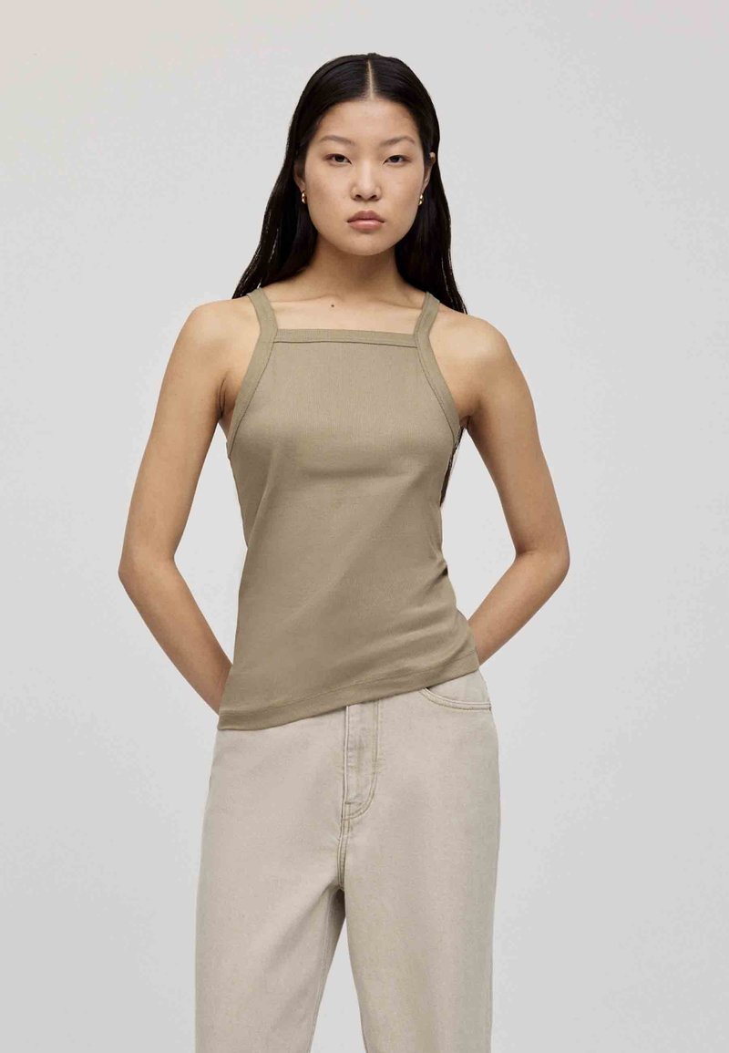 Beige ribbed tank top with square neckline and thin straps, paired with light-colored, relaxed-fit trousers. Smooth texture, minimal design.