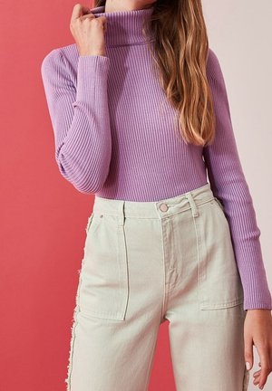 Långärmad, ribbad polotröja i lavendel, kombinerad med högmidjade, ljusgröna denimjeans med sidodetaljer och framfickor.