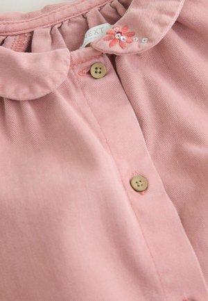 Pink collared dress featuring a ruffled neckline, two brown buttons, and floral embroidery with small sequins on the collar.