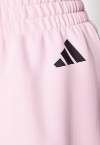 Shorts deportivos rosa hechos de tela suave, con una cintura elástica y un logo de Adidas negro en el lateral.