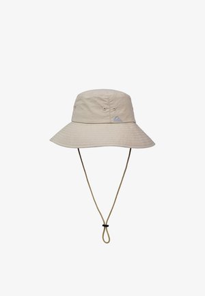 Beežist värvi ämbrimüts laia äärega, valmistatud kergest kangast. Omab reguleeritavat lõuakinnitust ja väikest brändi logo ees.