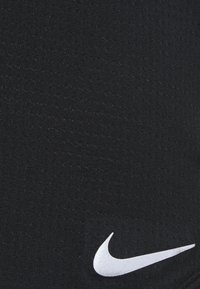 Tessuto sportivo nero con superficie testurizzata; presenta un logo Nike Swoosh bianco vicino all'angolo inferiore destro.