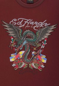 Bordowa koszulka z detalowym nadrukiem przedstawiającym smoka i tygrysy, ozdobiona żywymi kolorami i akcentami z kryształków.