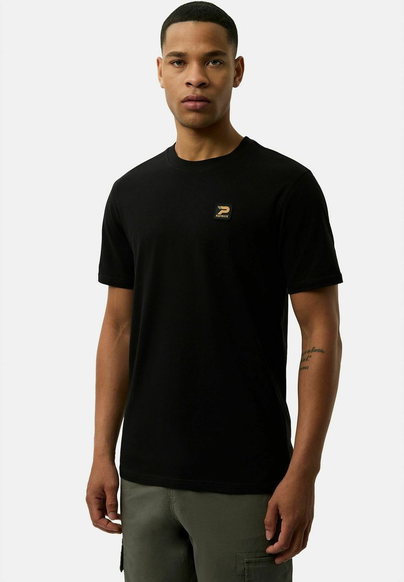 Czarny bawełniany t-shirt z krótkimi rękawami i okrągłym dekoltem. Posiada małą złotą naszywkę z logo w lewej części klatki piersiowej.