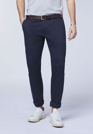 Navy chinos with a slim fit, featuring rolled cuffs, a leather belt with a patterned lining, and paired with white sneakers.